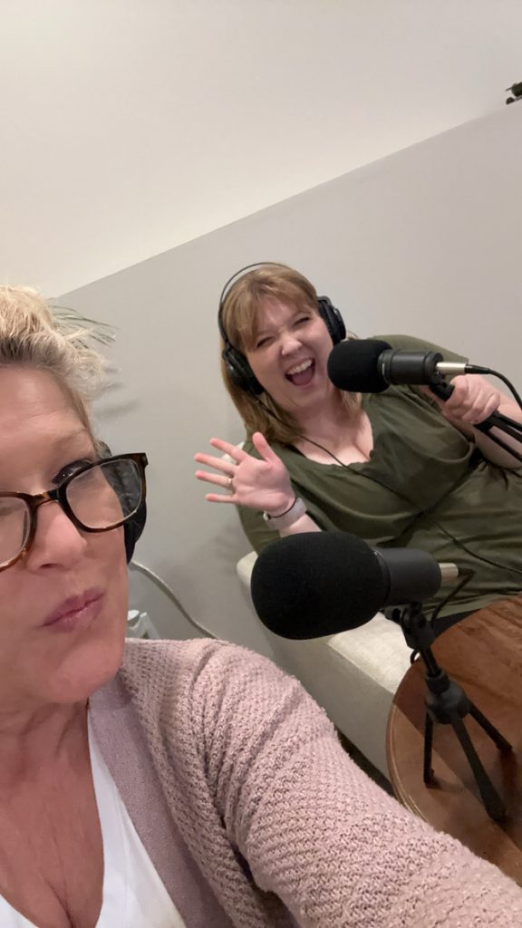 Mandy and Lauren recording The Empty Nest Mom podcast together, laughing and sharing real-life stories about motherhood and friendship.