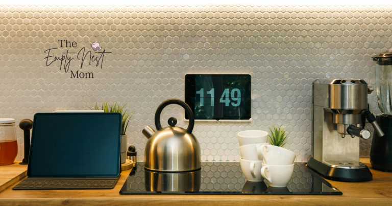 A cozy kitchen scene with a modern kettle, coffee cups, and tablet clock, styled with The Empty Nest Mom branding.