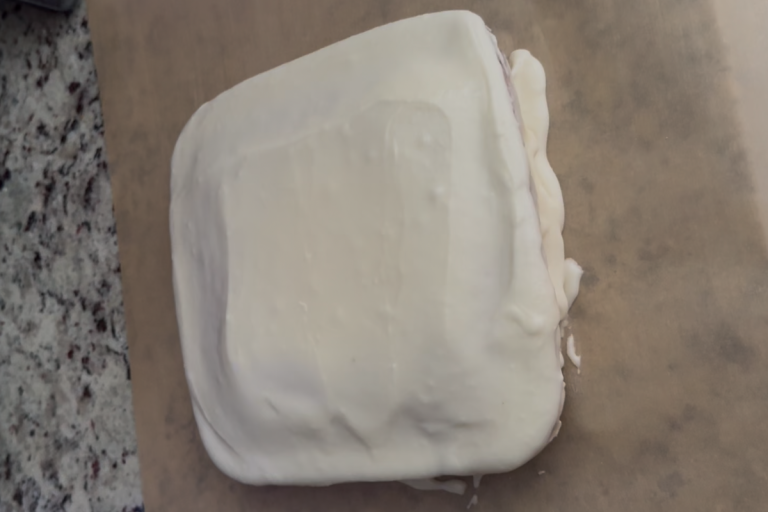 Homemade frosted cake on parchment paper, baked as a special family tradition each year.