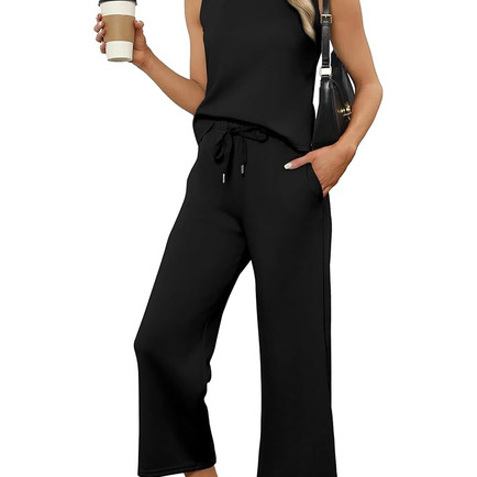 Woman wearing a black sleeveless lounge jumpsuit with wide-leg pants, holding a coffee cup and handbag — a comfy yet chic everyday outfit.