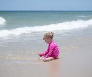 Quinn in a bright pink swimsuit playing at Gulf Shores Alabama beach