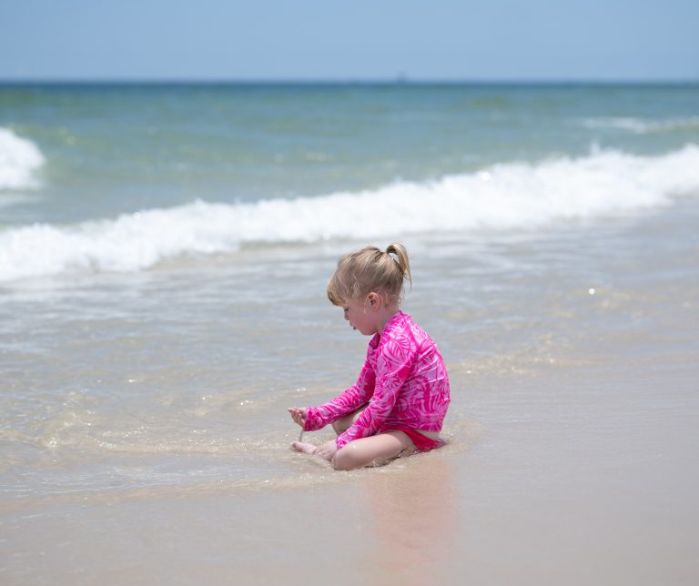 Quinn in a bright pink swimsuit playing at Gulf Shores Alabama beach