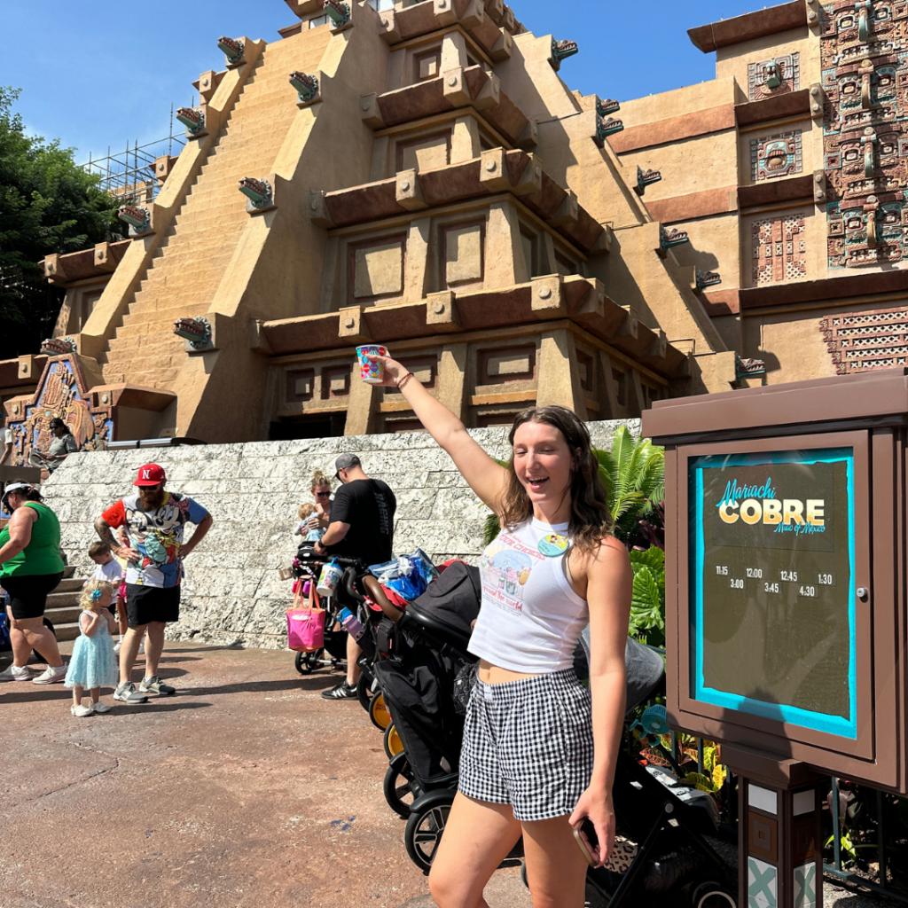 Gracie holding up her drink Water while in front of the Pyramid at Epcot